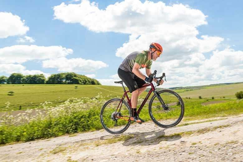 man biking uphill on an a/1, clouds and grass in background